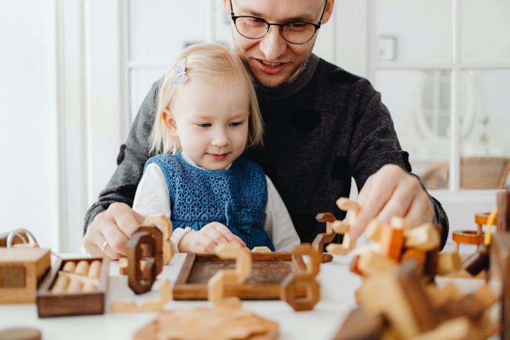 A father and daughter enjoying quality time playing with wooden toys indoors.